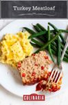A slice of turkey meatloaf on a white plate with mashed potatoes, green beans, and fork resting on the side.