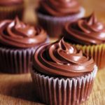 Five chocolate orange cupcakes with swirls of chocolate frosting on top.