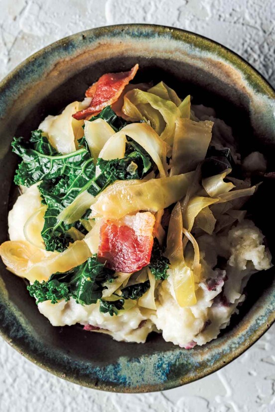 A ceramic bowl filled with colcannon - an Irish dish of mashed potatoes, cabbage, kale and bacon.