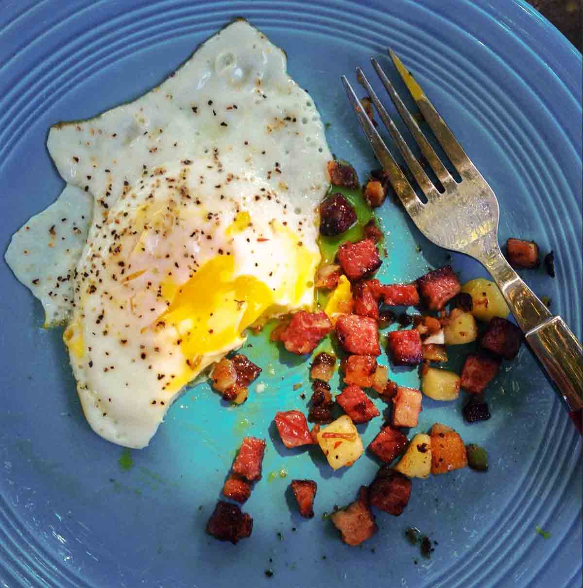 A blue plate with a fried egg and corned beef hash