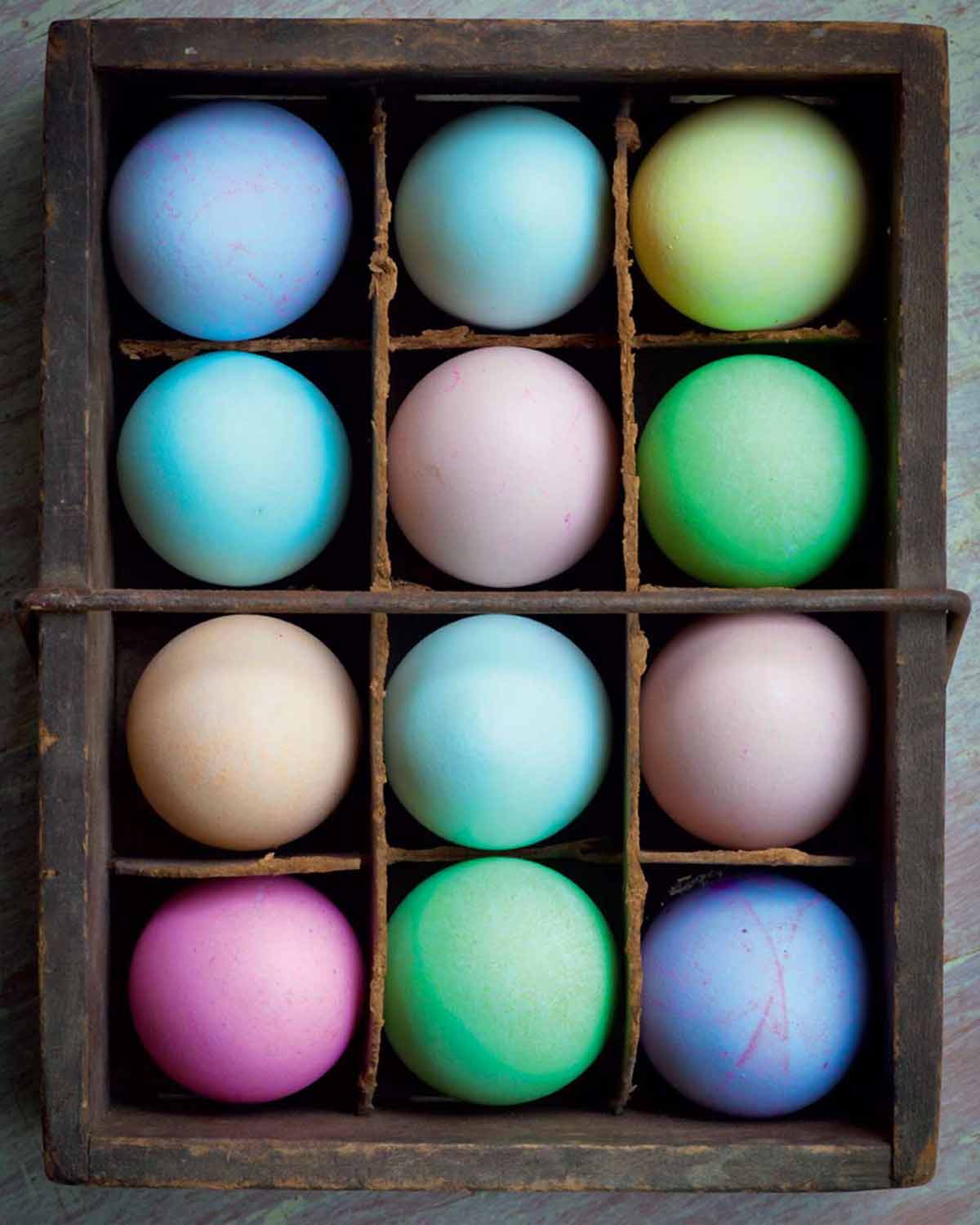 A crate filled with an assortment of dyed easter eggs.