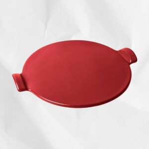 A red Emile Henry flame top pizza stone, one of the products for everything you need for pizza night at home.