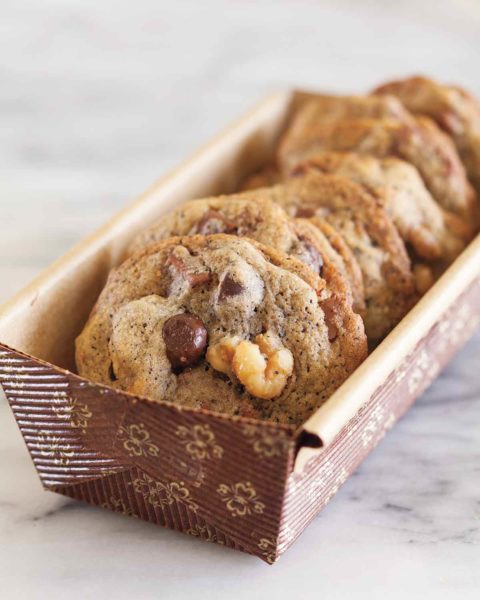 Several espresso chocolate chunk cookies in a paper container.