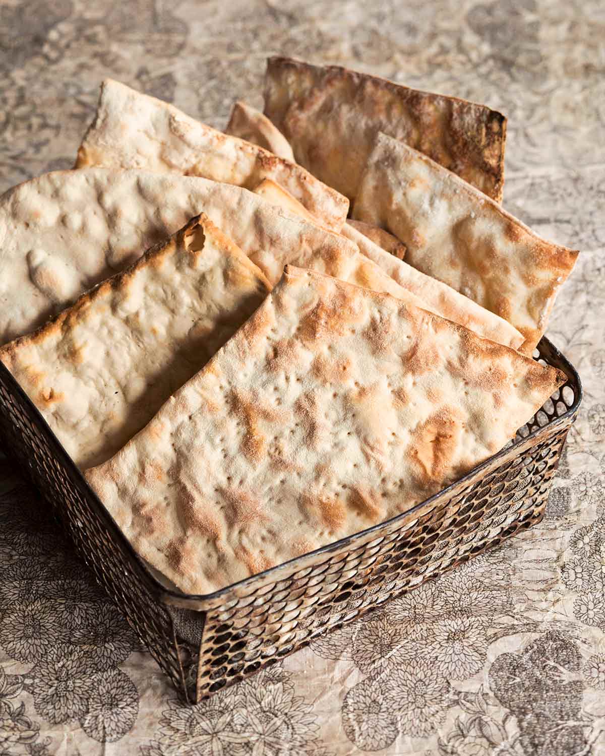 Sheets of homemade matzoh in a metal basket.