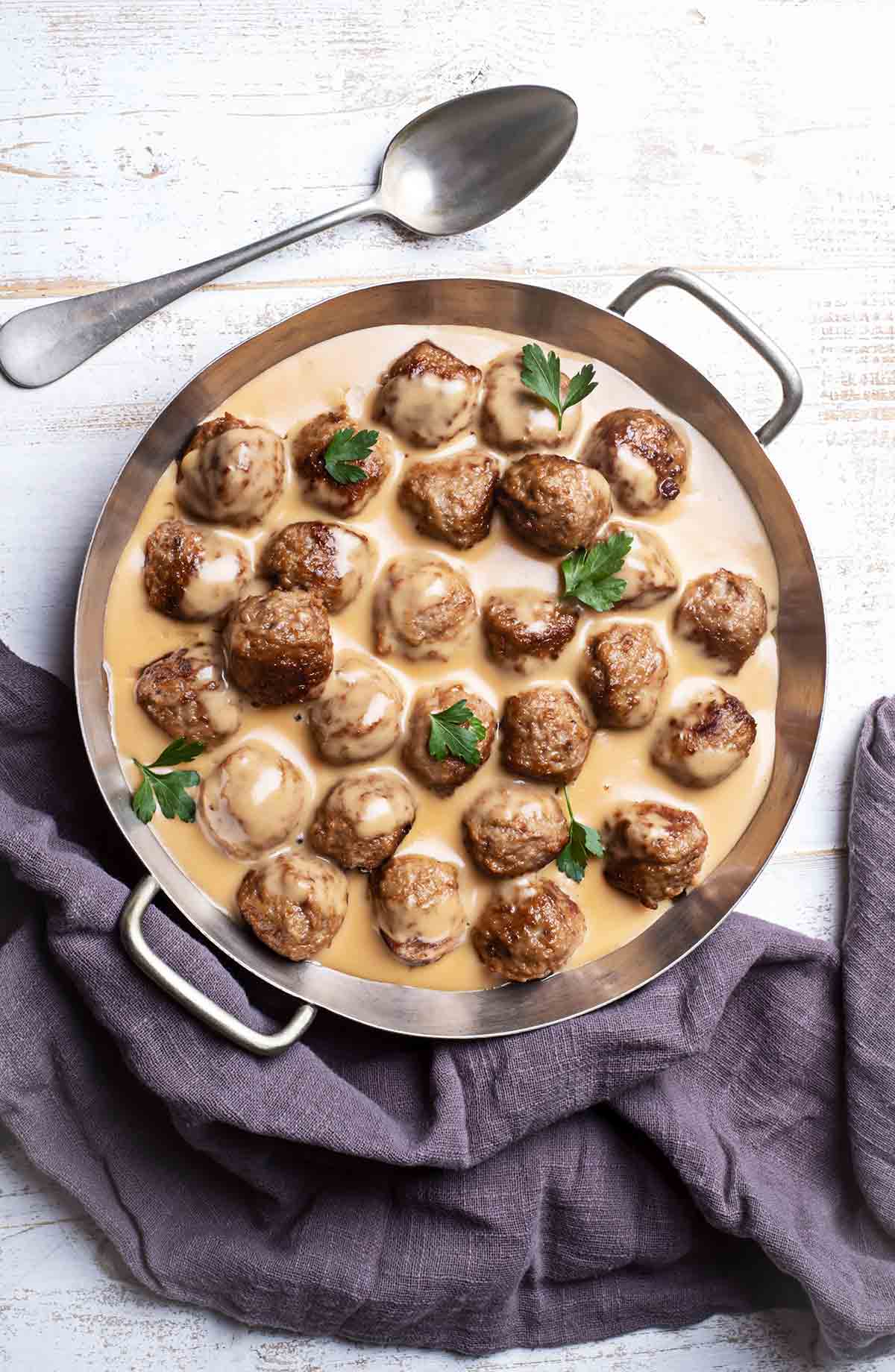 A skillet of homemade IKEA Swedish meatballs, cream gravy, and parsley.
