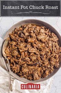 A bowl of shredded beef from an Instant Pot chuck roast with a silver spoon resting in the bowl.