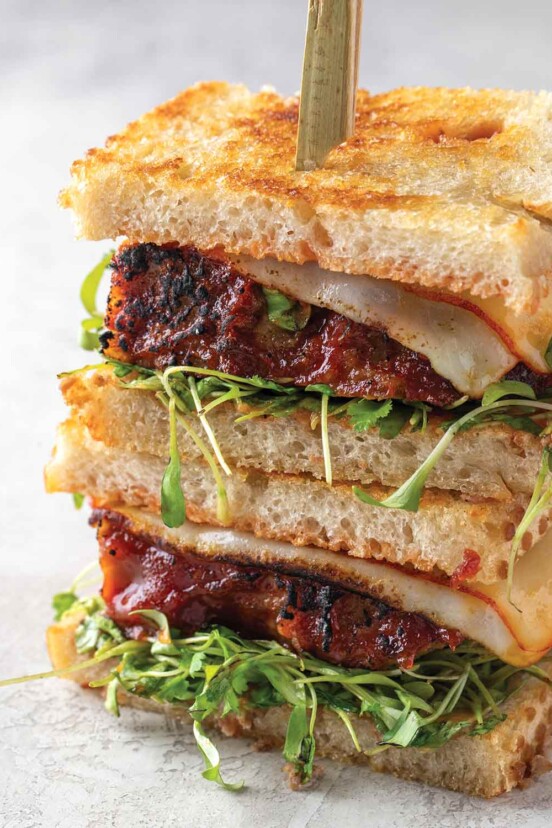 Two halves of a leftover meatloaf sandwich stacked on top of each other and held together with a wooden skewer.