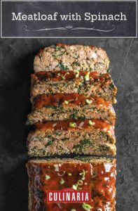 A cooked meatloaf with spinach with four slices cut from it.