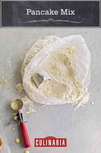 A plastic bag filled with homemade pancake mix and cup resting in the mix and a wet ice cream scoop on the side.