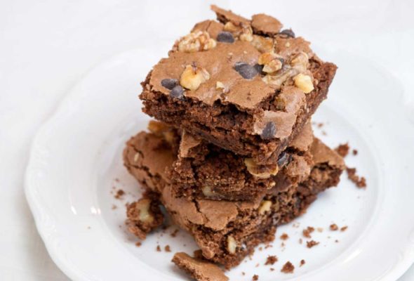 Three Passover brownies stacked on top of each other on a white plate.