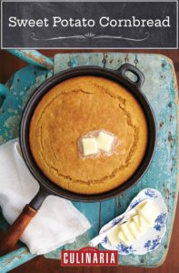 A cast-iron skillet filled with a cooked sweet potato cornbread with two pats of butter on top and a dish of butter pats beside it.