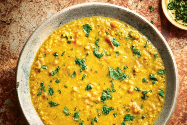 A ceramic bowl filled with tarka dal and sprinkled with cilantro with a small bowl of chopped cilantro on the side.