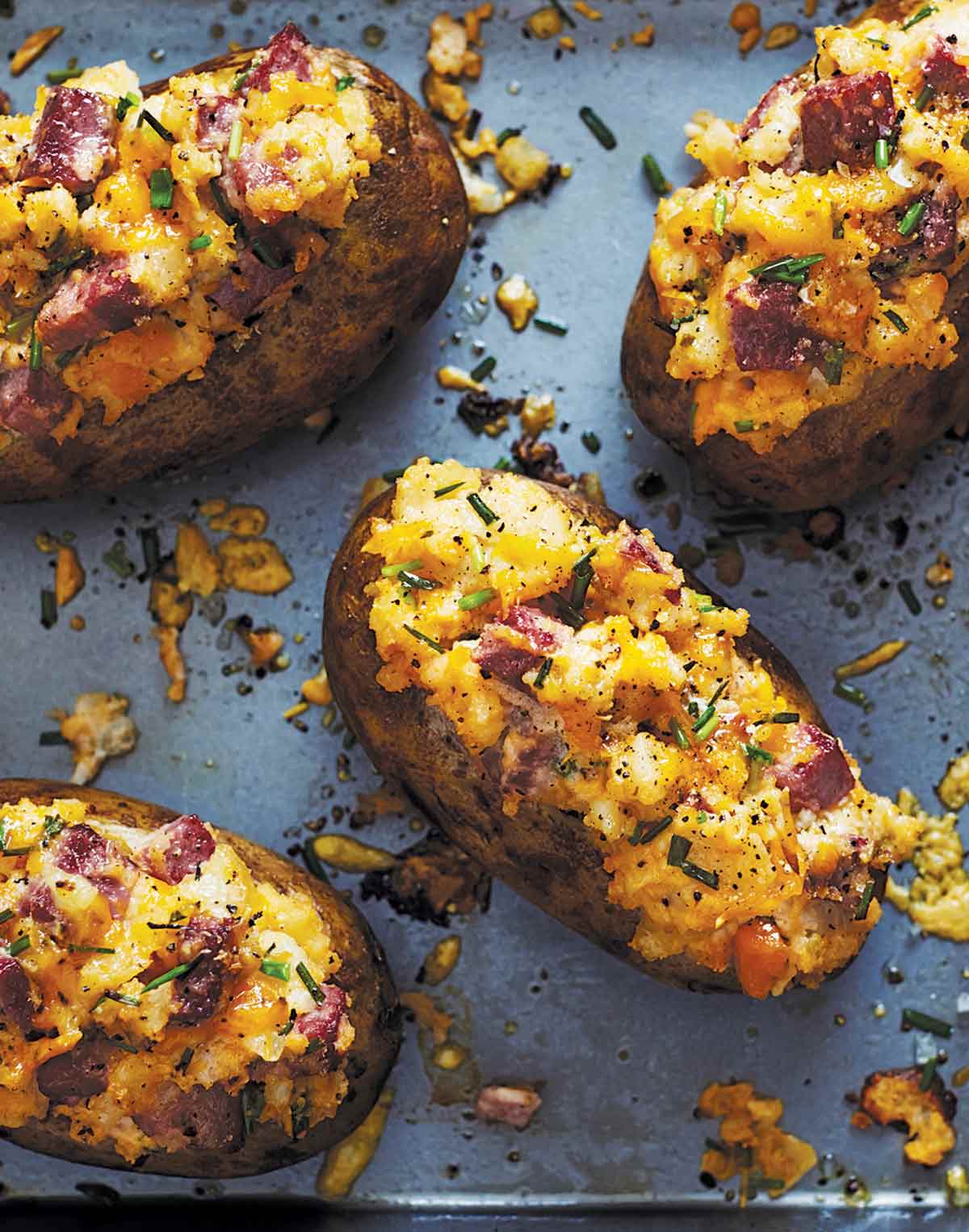 Four twice baked potatoes with corned beef on a baking sheet.