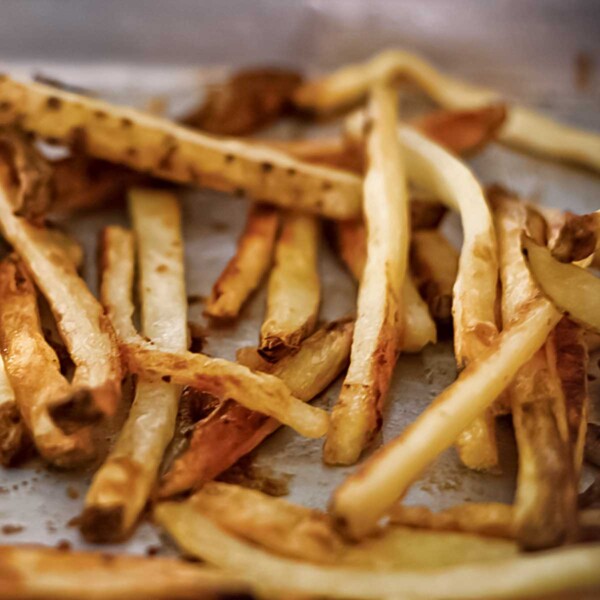 A tangle of baked fries on a rimmed baking sheet.