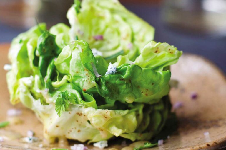 A salad of butter lettuce with maytag blue cheese on a brown plate.