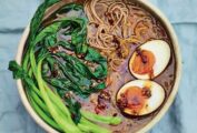 A bowl of caramelized onion ramen with chile, choy sum, and soft boiled egg.