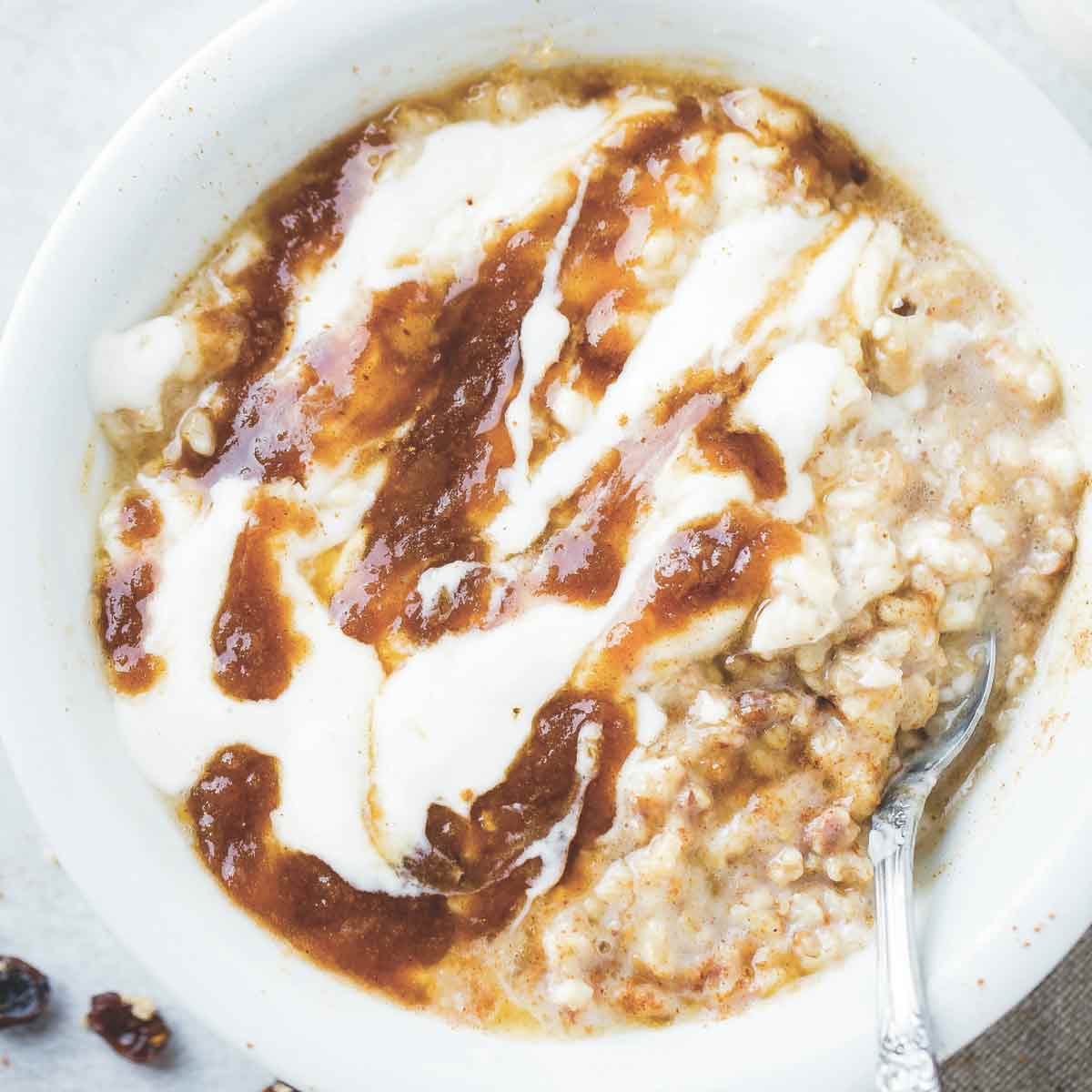 A bowl of cinnamon roll oatmeal with brown sugar swirl and yogurt drizzled over the top.