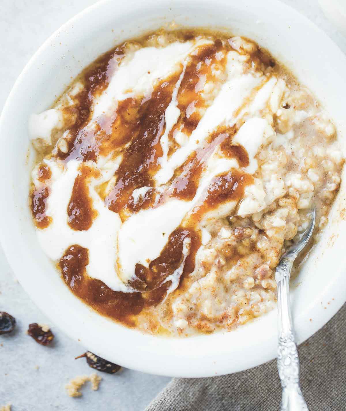 A bowl of cinnamon roll oatmeal with brown sugar swirl and yogurt drizzled over the top.