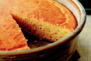 A cake pan of golden brown cornbread with a slice removed