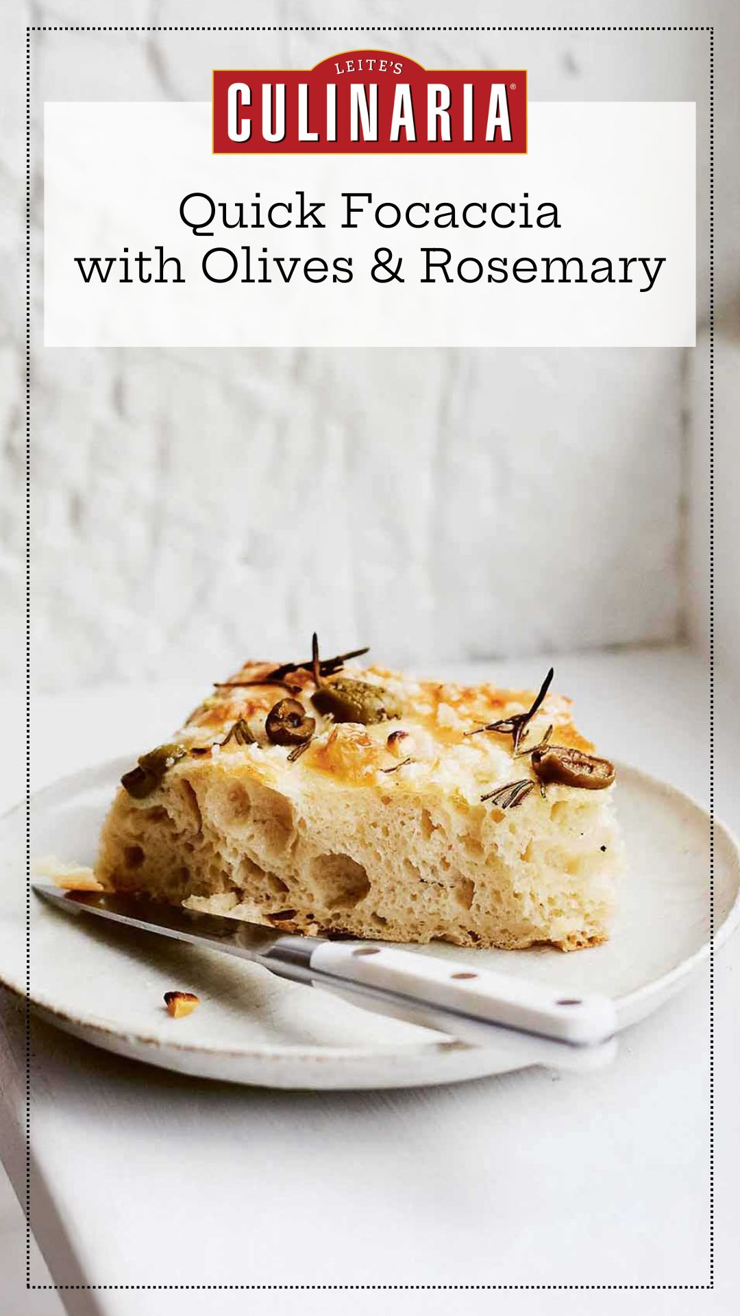 A slice of focaccia with olives and rosemary on a white plate with a knife resting beside it.