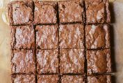 A batch of gluten-free brownies with soy sauce or tamari cut into 16 squares on a piece of parchment.