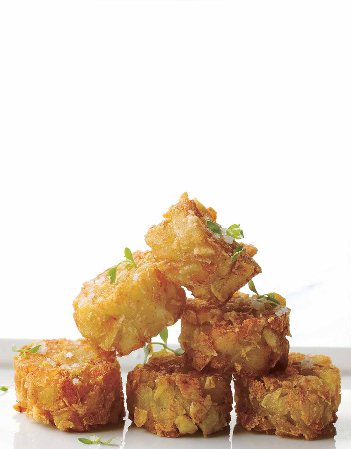 A stack of six homemade tater tots, sprinkled with sea salt.