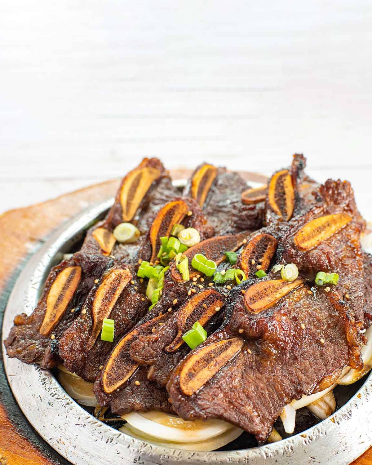 Strips of Korean beef barbecue on a platter, garnished with green onions and sesame seeds.