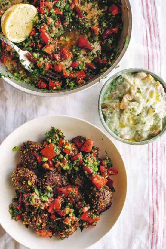 A white bowl filled with lamb kofte and parsley and tomato salad.