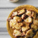Wooden bowl of octopus with paprika, bowl of paprika, cruet of olive oil