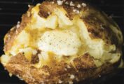 Three perfect baked potatoes coated in flaked salt and squeezed open with a pat of butter in the center.