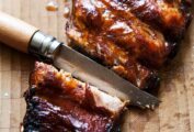 A slab of glazed pressure cooker ribs with a knife cutting between two ribs