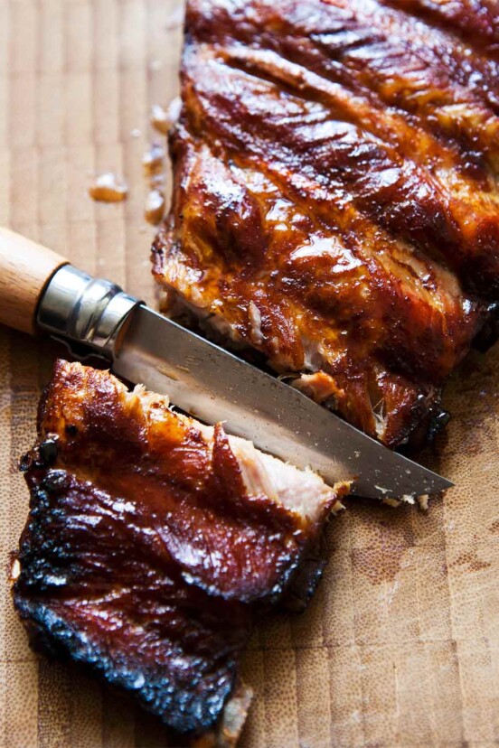 A slab of glazed pressure cooker ribs with a knife cutting between two ribs