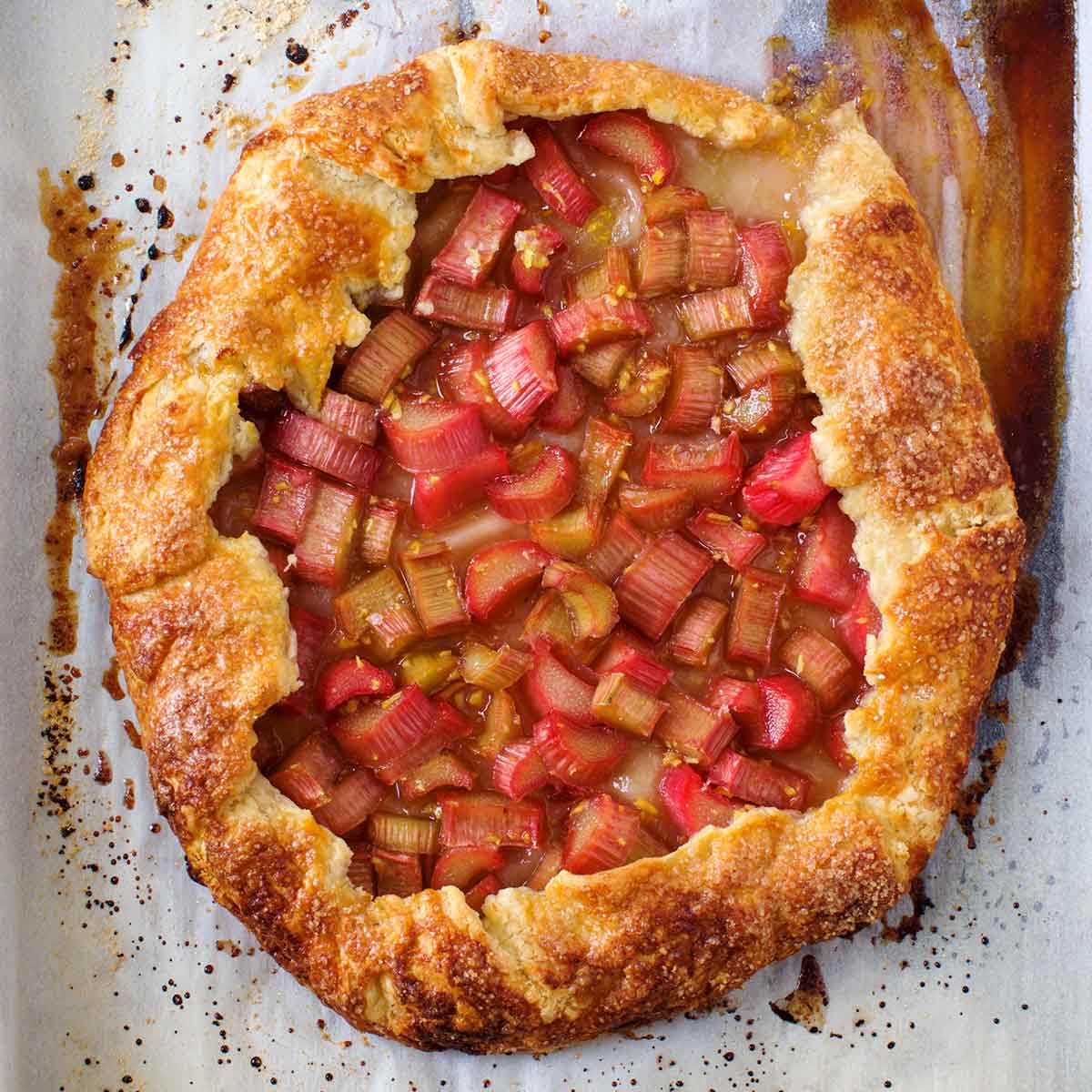 A whole baked rhubarb-ginger crostata on a piece of parchment paper.