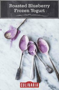 Several spoons with melted roasted blueberry frozen yogurt on them on a white marble surface.