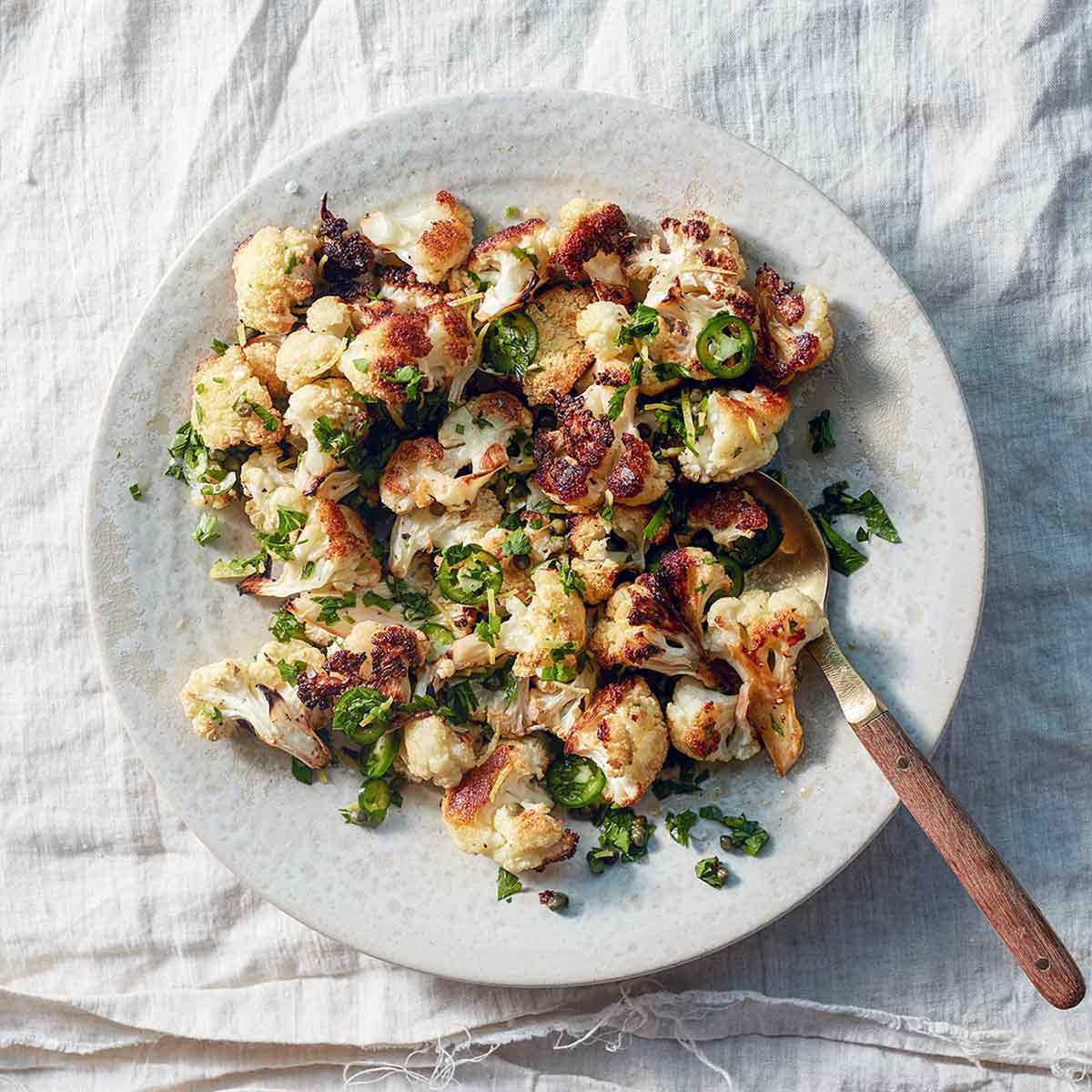 A white plate topped with roasted cauliflower with jalapeño and capers.