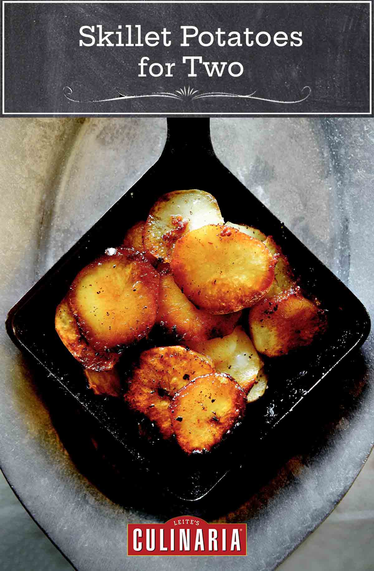 A square cast iron skillet filled with sliced fried skillet potatoes for 2 on a grey oval metal platter.