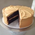 A sour cream mocha cake with espresso frosting on a cake stand with a slice cut from it.