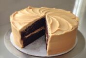 A sour cream mocha cake with espresso frosting on a cake stand with a slice cut from it.