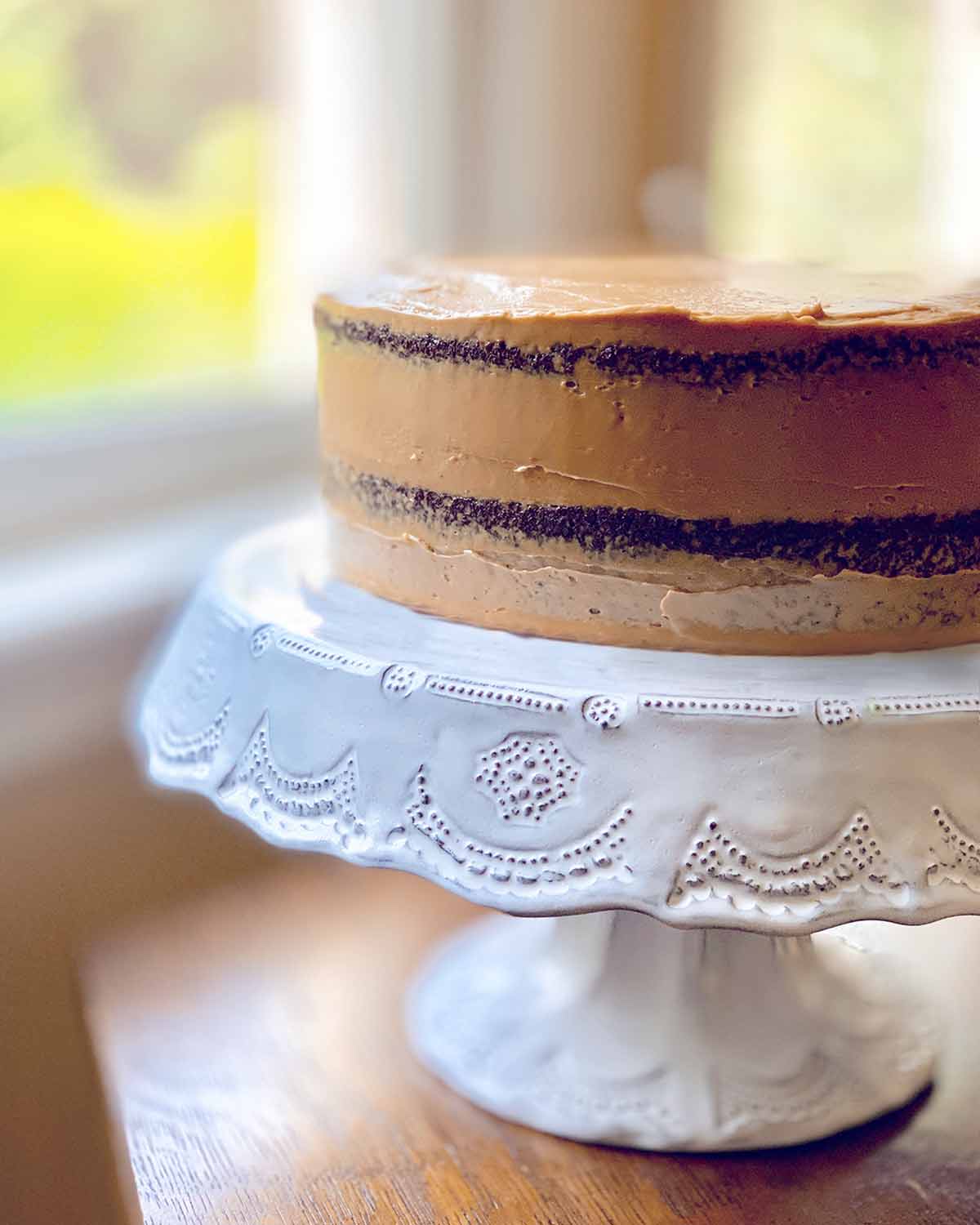 A whole sour cream mocha cake on a white decorative cake stand.