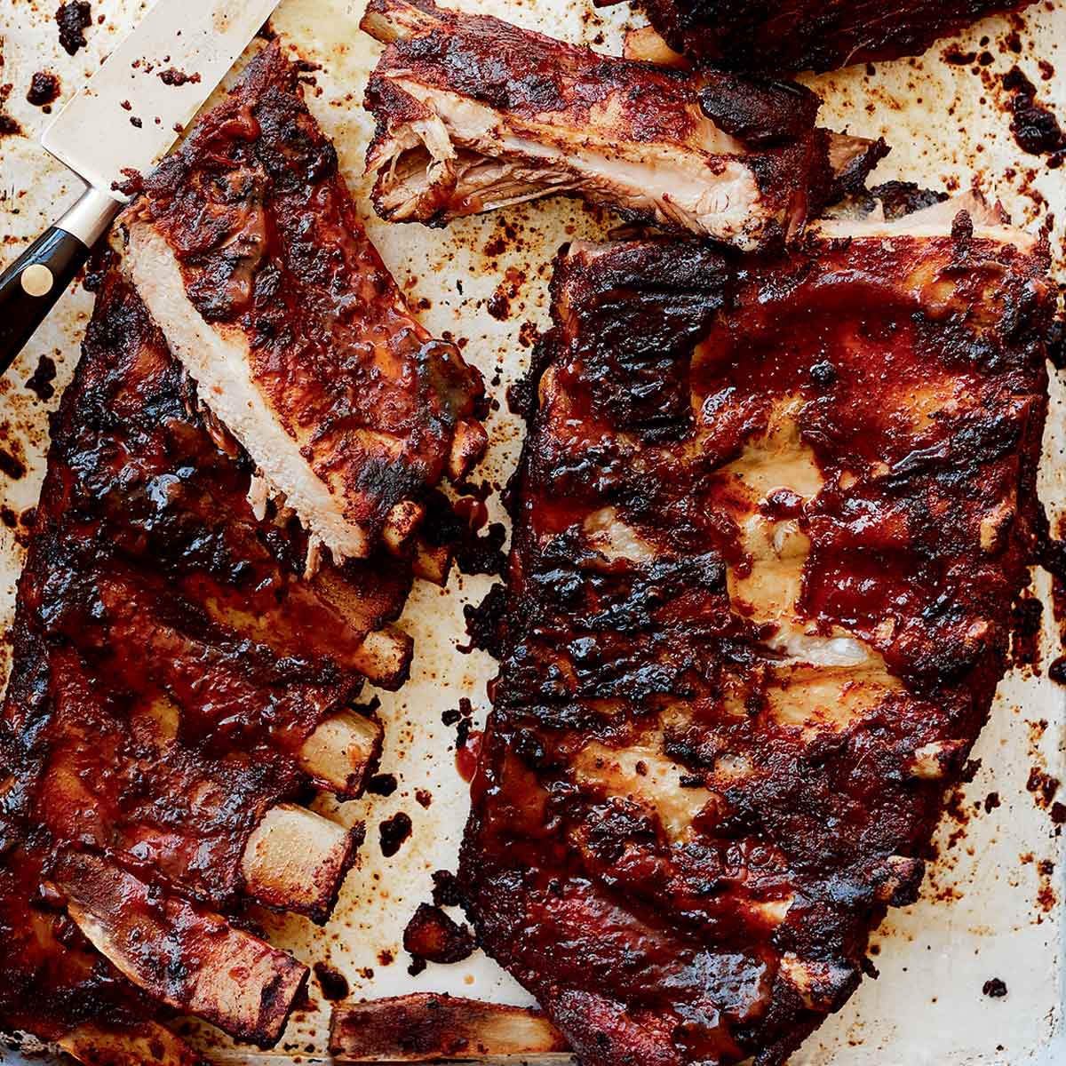 Two slabs of St. Louis style ribs from Alex Guarnaschelli with some cut into individual ribs and a knife lying in the middle.