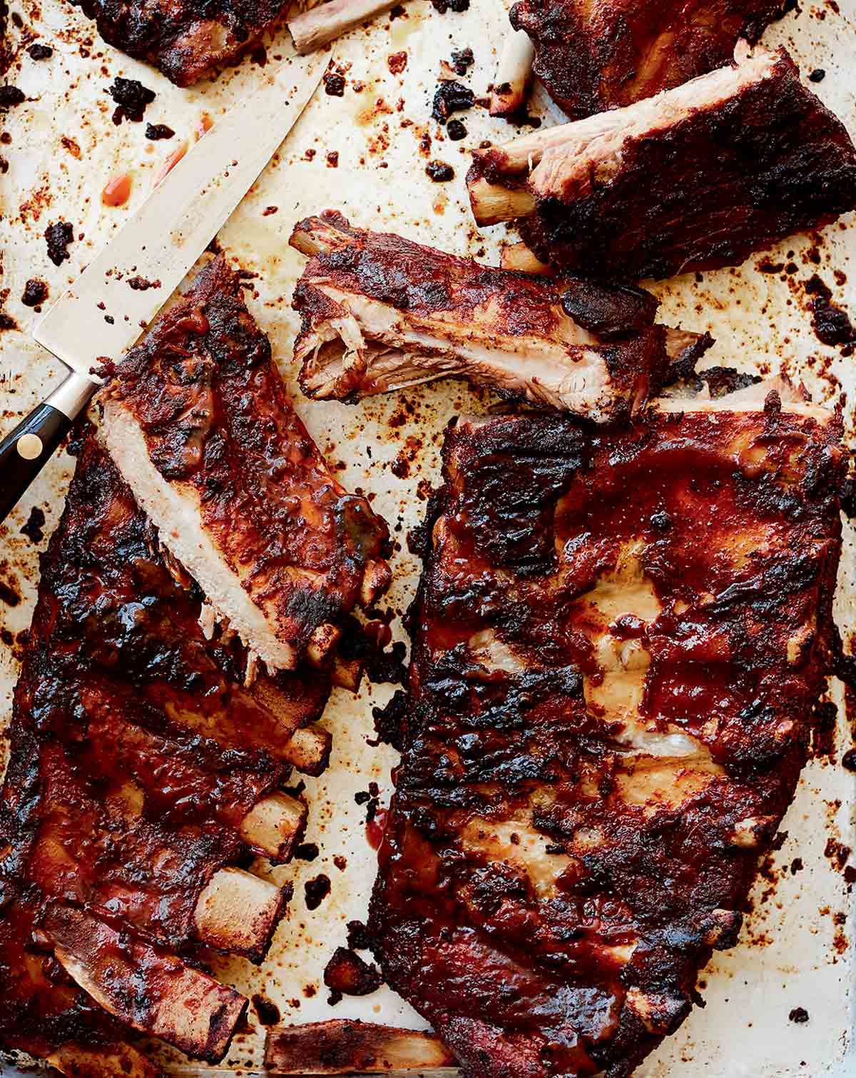 Two slabs of St. Louis style ribs with some cut into individual ribs and a knife lying in the middle.
