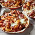Three round casserole dishes filled with baked pasta with tomatoes and eggplant.
