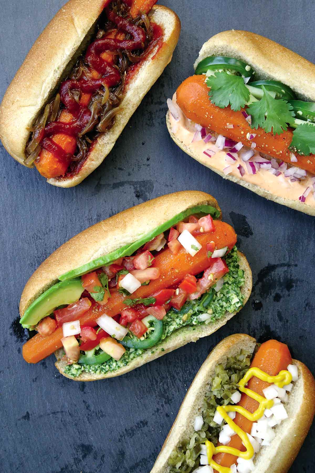 Four carrot hot dogs filled with assorted garnishes.