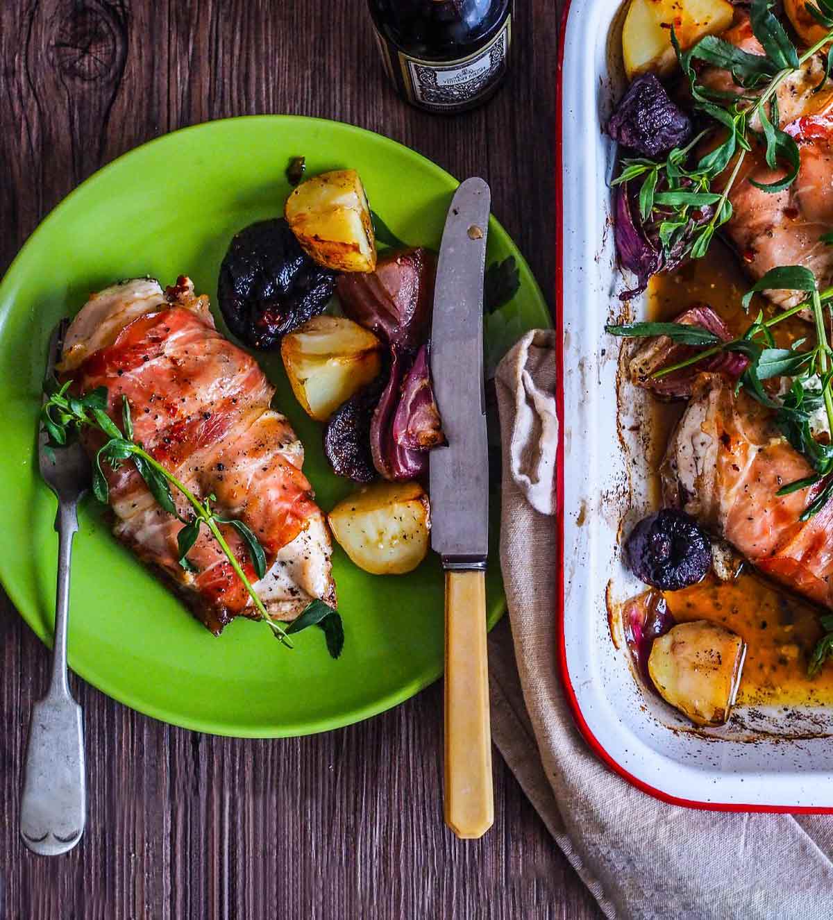 A green plate topped with a chicken breast stuffed with fresh figs and goat cheese and some roasted root vegetables alongside.