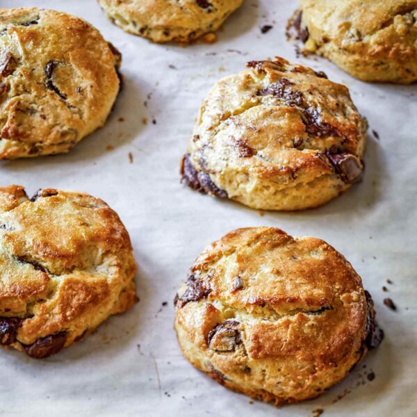 A baking sheet with seven chocolate pecan scones.
