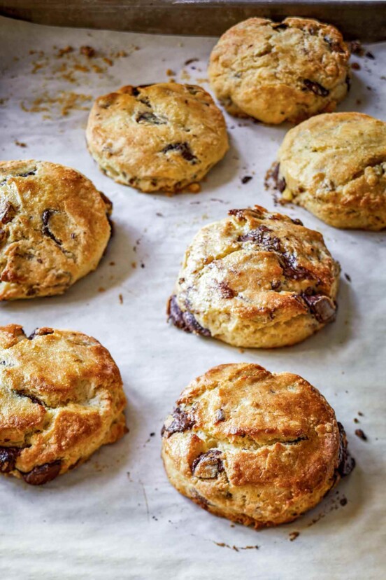 A baking sheet with seven chocolate pecan scones.
