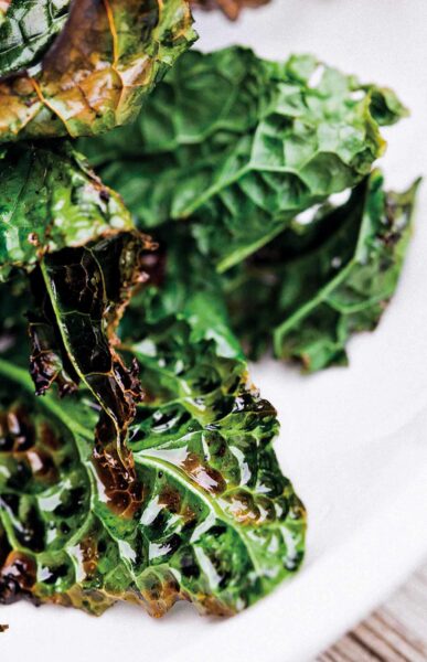 A few pieces of grilled kale stacked on a white plate.