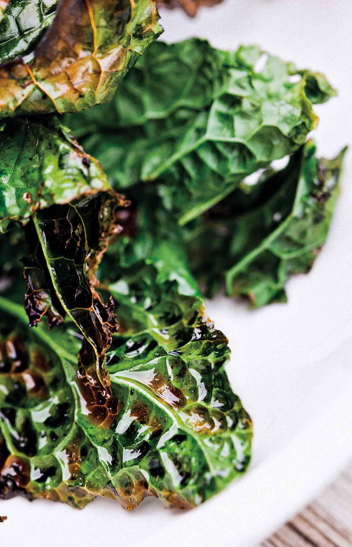 A few pieces of grilled kale stacked on a white plate.