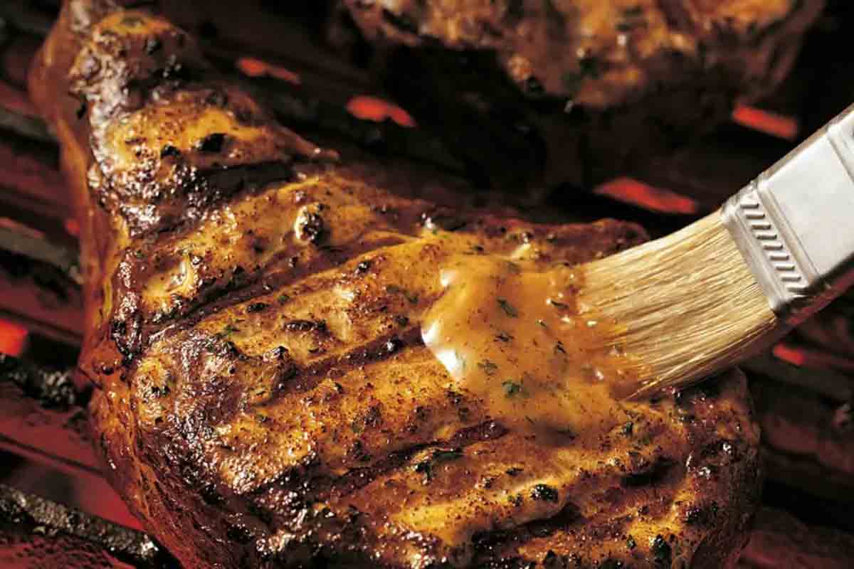 Grilling tips: a pork chop being brushed with a mayo-herb glaze