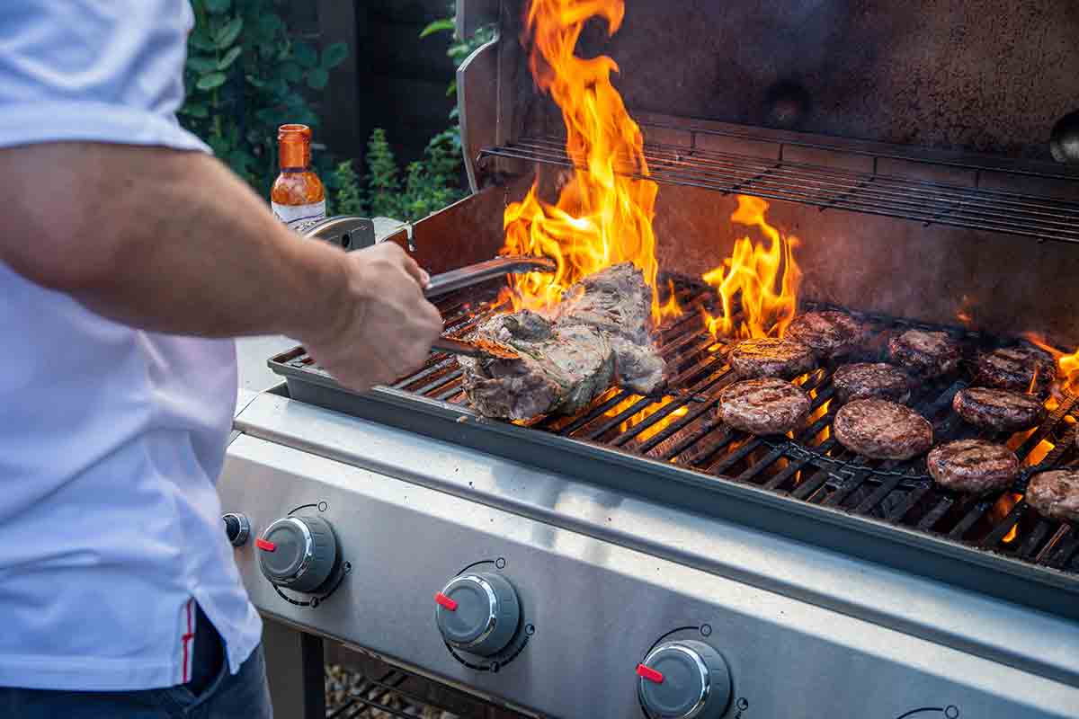Grilling tip: a man at a gas grill with a big flare-up